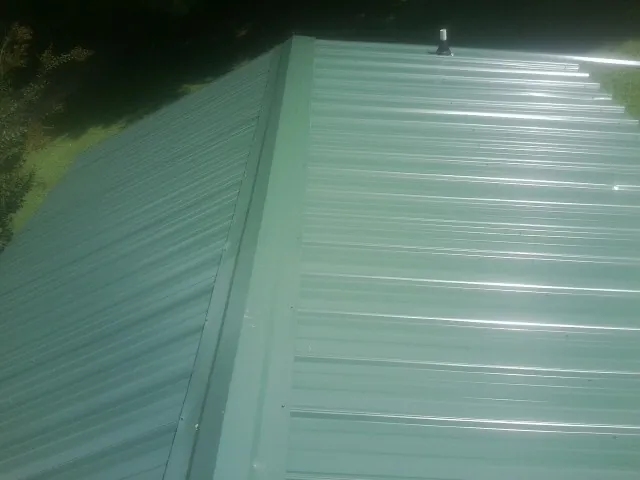 New green metal panels meeting at the ridge of a roof — Flat Roof Repair work by our crew in Dunmor