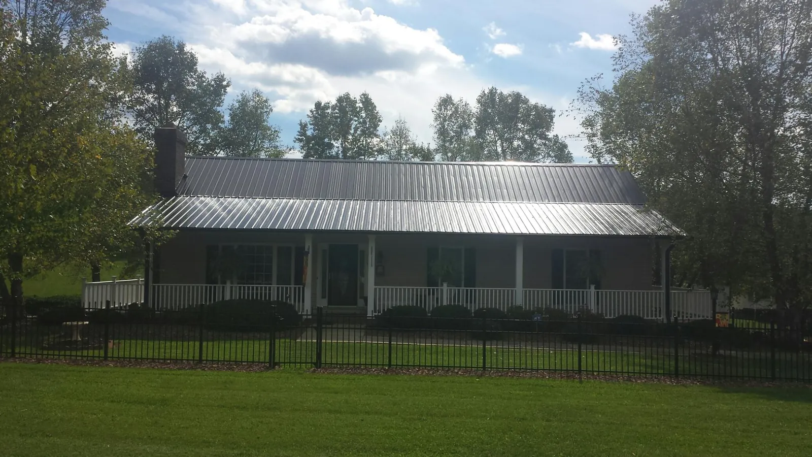 Gray metal roof on a brick ranch with a full width front porch — Gutter Guard Installation work by our crew in Dunmor