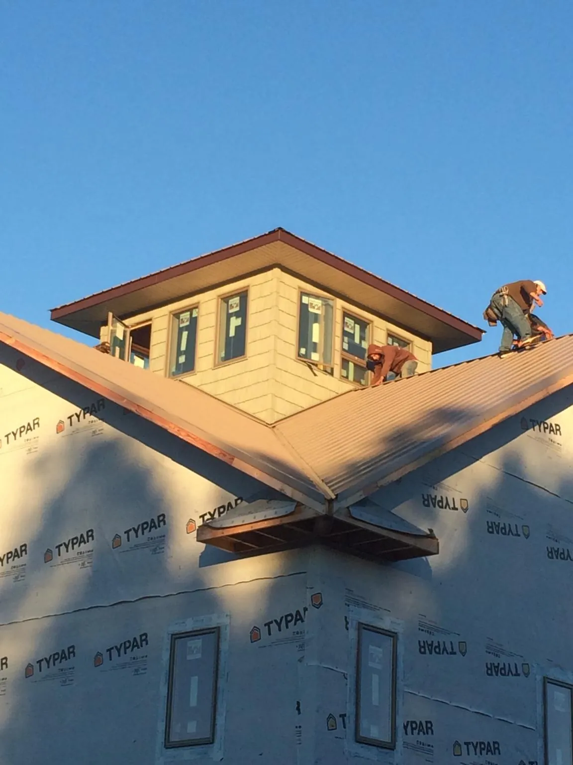 Roofers working around a rooftop cupola on a new metal roof at sunset — Roof Waterproofing in Dunmor by Roofing Brothers